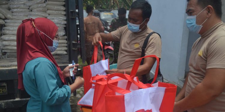 Sejumlah masyarakat terlihat menerima bantuan beras yang diberikan pihak Kepolisian usai melaksanakan vaksinasi di Halaman belakang Kantor Desa Yosonegoro, Kecamatan Limboto Barat, Kabupaten Gorontalo, Kamis (23/9/2021). Foto : Putra/Gopos.