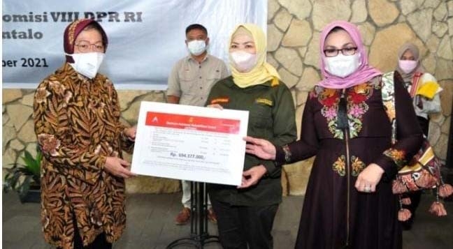 Mensos Risma (kiri) menyerahkan bantuan ATENSI kepada Anggota Komisi VIII DPR RI, Idah Syahidah Rusli Habibie (tengah), di Angelato Resto & Cafe, Kota Gorontalo, Kamis (30/9/2021). (Foto: Haris)