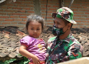 Anggota Satgas TMMD saat menggendong anak-anak di Desa Pakisaji, Kecamatan Kademangan, Kabupaten Blitar, Rabu (22/9/2021). (Foto: dok.kodim 0808/Blitar)