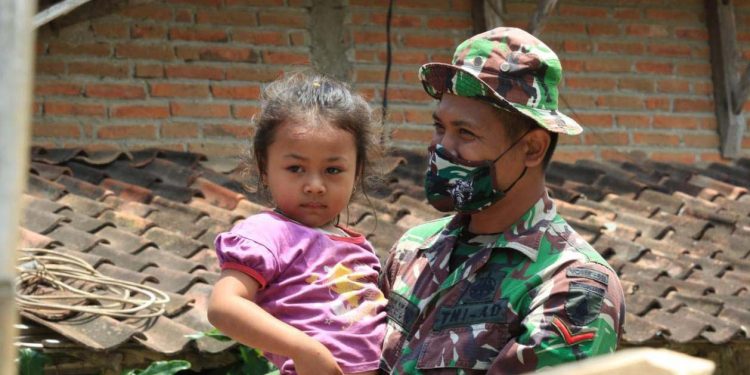 Anggota Satgas TMMD saat menggendong anak-anak di Desa Pakisaji, Kecamatan Kademangan, Kabupaten Blitar, Rabu (22/9/2021). (Foto: dok.kodim 0808/Blitar)