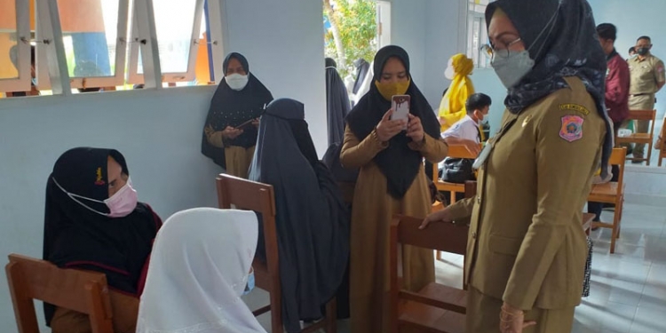 Wakil Bupati Bone Bolango, Merlan S. Uloli saat berbincang dengan para siswa serta orang tua pada hari pertama pembukaan sekolah yang dirangkaikan dengan pelaksanaan vaksinasi. (Foto Indra/Gopos)