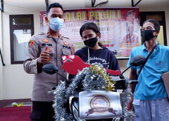 Kapolsek Kota Barat, Ipda Andi Wiranata Tamba (Kiri) bersama Nurain Jailani (tengah) saat penyerahan doorprize utama berupa sepeda motor dalam kegiatan vaksinasi di Polsek Kota Barat, Kota Gorontalo, Senin (27/9/2021). (istimewa)