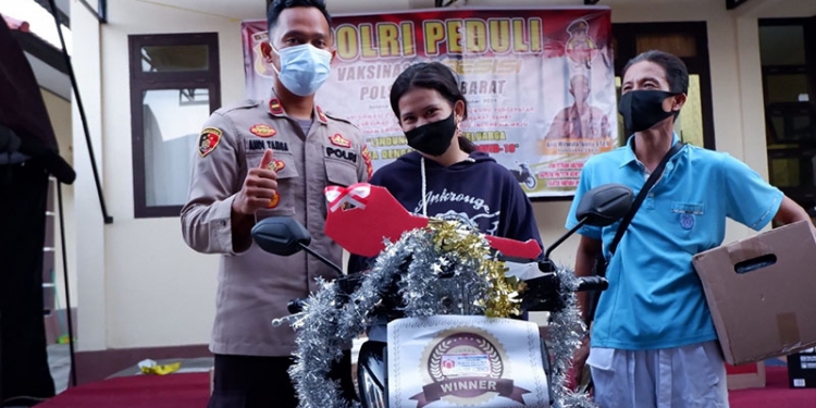 Kapolsek Kota Barat, Ipda Andi Wiranata Tamba (Kiri) bersama Nurain Jailani (tengah) saat penyerahan doorprize utama berupa sepeda motor dalam kegiatan vaksinasi di Polsek Kota Barat, Kota Gorontalo, Senin (27/9/2021). (istimewa)