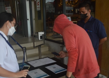 Salah seorang pengunjung mall Gorontalo melakukan scan QR Code untuk memastikan apakah bisa masuk atau tidak ke dalam gedung mall. (Putra/gopos)