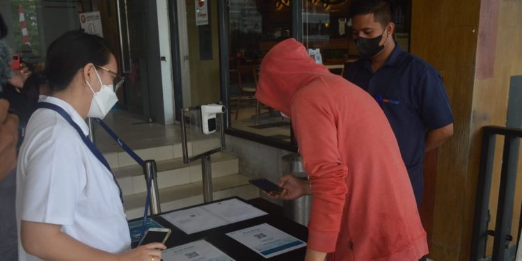 Salah seorang pengunjung mall Gorontalo melakukan scan QR Code untuk memastikan apakah bisa masuk atau tidak ke dalam gedung mall. (Putra/gopos)