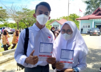 Michael dan Najwa, dua siswa SMAN 1 Paguat memperlihatkan kartu kontrol vaksinasi dosis I usai divaksin di Pelabuhan Bumbulan, Kecamatan Paguat, Kabupaten Pohuwato, Rabu (1/9/2021). (Foto: Vivi-Kominfo).
