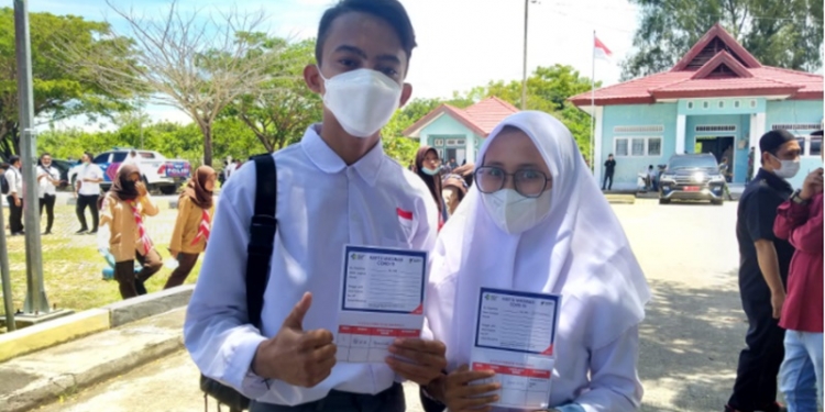 Michael dan Najwa, dua siswa SMAN 1 Paguat memperlihatkan kartu kontrol vaksinasi dosis I usai divaksin di Pelabuhan Bumbulan, Kecamatan Paguat, Kabupaten Pohuwato, Rabu (1/9/2021). (Foto: Vivi-Kominfo).