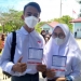 Michael dan Najwa, dua siswa SMAN 1 Paguat memperlihatkan kartu kontrol vaksinasi dosis I usai divaksin di Pelabuhan Bumbulan, Kecamatan Paguat, Kabupaten Pohuwato, Rabu (1/9/2021). (Foto: Vivi-Kominfo).
