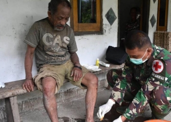 Serka Firman saat mengobati luka seorang kakek, Haryn Kalami, warga Desa Tulabolo, Kecamatan Suwawa Timur, Kabupaten Bone Bolango, yang mengalami terpeleset ke dalam jurang ketika perjalanan menuju ke kebun. (Foto: Istimewa)