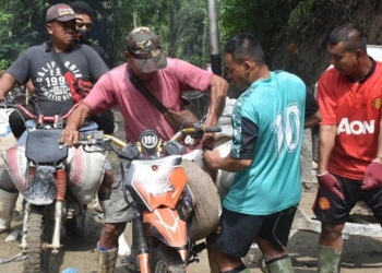 Warga Desa Tulabolo yang kesehariannya bekerja menjadi tukang ojek bersedia menjadi tukang ojek material untuk keperluan pengecoran jalan di desanya yang dibangun melalui program TMMD ke-112 Kodim 1304/Gorontalo. (Foto Istimewa)
