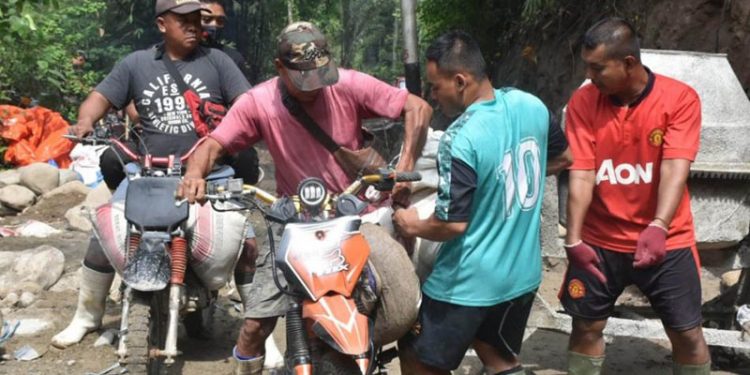 Warga Desa Tulabolo yang kesehariannya bekerja menjadi tukang ojek bersedia menjadi tukang ojek material untuk keperluan pengecoran jalan di desanya yang dibangun melalui program TMMD ke-112 Kodim 1304/Gorontalo. (Foto Istimewa)
