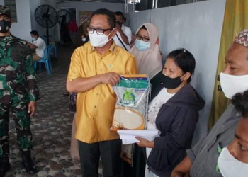 Irwan Hunawa, sedang menyerahkan bantuan berupa beras kepada peserta yang telah divaksin Covid-19, Senin (11/10/2021). (Foto: Humas Dekot)