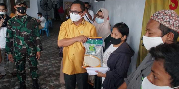 Irwan Hunawa, sedang menyerahkan bantuan berupa beras kepada peserta yang telah divaksin Covid-19, Senin (11/10/2021). (Foto: Humas Dekot)