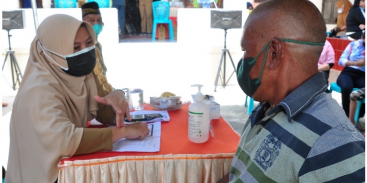 Seorang petugas kesehatan (kiri) memeriksa kesehatan seorang warga yang akan mengikuti vaksinasi COVID-19 di halaman RAL FM Gorontalo, Kelurahan Ipilo, Kota Timur, Kota Gorontalo, Senin (18/10/2021). (Foto: Haris)