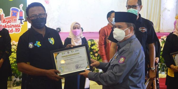 Wakil Gubernur Gorontalo, Idris Rahim saat menyerahkan penghargaan kepada salah satu elemen kesehatan di Provinsi Gorontalo di  peringatan HKN Ke-57 di Grand Sumberia Ballroom, Jumat (12/11/2021). (Foto : Putra/Gopos)