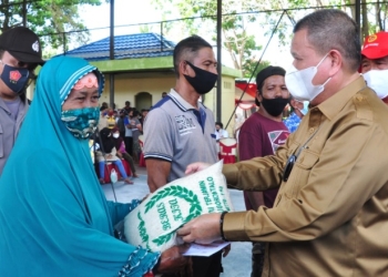 Idris Rahim (kanan), menyerahkan bantuan beras kepada warga yang mengikuti vaksinasi massal yang digelar oleh Binda Provinsi Gorontalo di Kecamatan Tilamuta, Kabupaten Boalemo. (Foto: Haris)