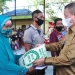 Idris Rahim (kanan), menyerahkan bantuan beras kepada warga yang mengikuti vaksinasi massal yang digelar oleh Binda Provinsi Gorontalo di Kecamatan Tilamuta, Kabupaten Boalemo. (Foto: Haris)