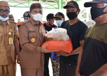 Bupati Pohuwato, Saipul Mbuinga, menyerahkan bantuan banjir rob kepada warga yang terdampak bencana banjir rob. (istimewa)