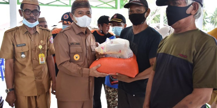 Bupati Pohuwato, Saipul Mbuinga, menyerahkan bantuan banjir rob kepada warga yang terdampak bencana banjir rob. (istimewa)