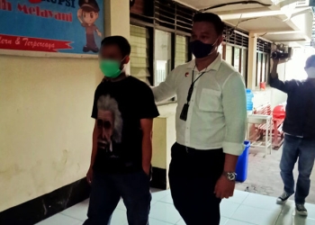 Tersangka JK (kiri) berjalan didampingi petugas Polres Gorontalo Kota menuju ke ruang tahanan Polres Gorontalo Kota, Senin (24/1/2022). (sari/gopos)