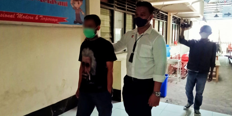Tersangka JK (kiri) berjalan didampingi petugas Polres Gorontalo Kota menuju ke ruang tahanan Polres Gorontalo Kota, Senin (24/1/2022). (sari/gopos)