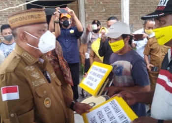 Gubernur Gorontalo, Rusli Habibie (Kiri) saat menyerahkan satu unit Rice Milling Unit (RMU) kepada kelompok tani Bina Tunas Idah di desa Sukamaju, kecamatan Wonosari, kabupaten Boalemo, Senin (3/1/2022). (Foto: Isam).