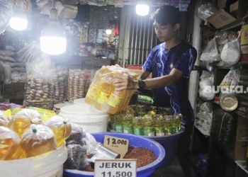 Pedagang menata minyak goreng kemasan di tokonya di Pasar Minggu, Jakarta, Rabu (26/1/2022). [Suara.com]