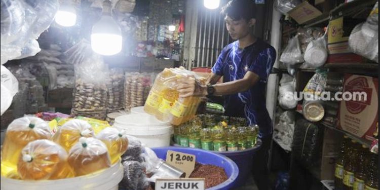 Pedagang menata minyak goreng kemasan di tokonya di Pasar Minggu, Jakarta, Rabu (26/1/2022). [Suara.com]