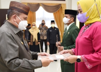Wagub Gorontalo Idris Rahim (kiri) saatmenyerahkan SK Gubernur Gorontalo kepada pejabat yang dilantik di aula rumah jabatan Gubernur Gorontalo, Jumat (31/12/2021). (Foto : Haris)