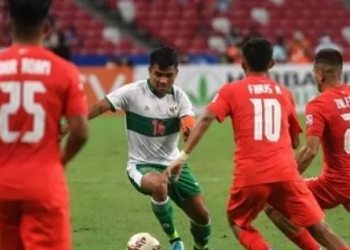 Asnawi Mangkualam Bahar (kedua dari kiri) mencoba melewati pemain Singapura Faris Ramli (kedua dari kanan) dan Zulfahmi Arifin (kanan) pada leg pertama semifinal Piala AFF 2020 antara Singapura dan Indonesia di Stadion Nasional di Singapura pada 22 Desember 2021. Roslan RAHMAN / AFP