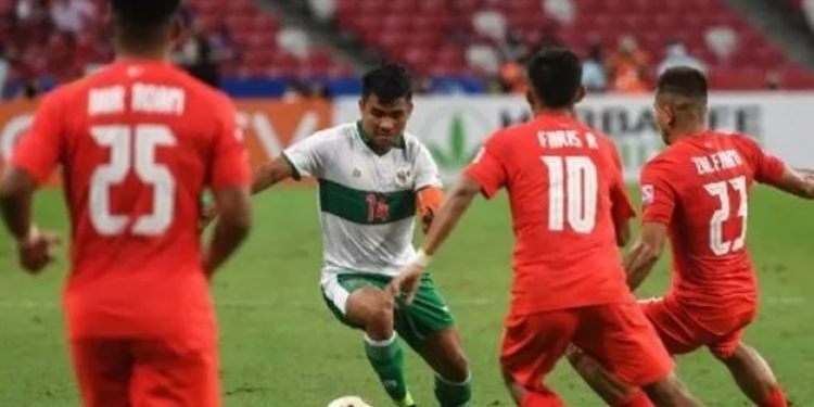 Asnawi Mangkualam Bahar (kedua dari kiri) mencoba melewati pemain Singapura Faris Ramli (kedua dari kanan) dan Zulfahmi Arifin (kanan) pada leg pertama semifinal Piala AFF 2020 antara Singapura dan Indonesia di Stadion Nasional di Singapura pada 22 Desember 2021. Roslan RAHMAN / AFP