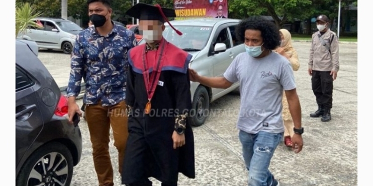 JK menjalani prosesi wisuda dikawal oleh dua polisi karena berstatus tahanan, Rabu (23/2/2022) (hms/polres)