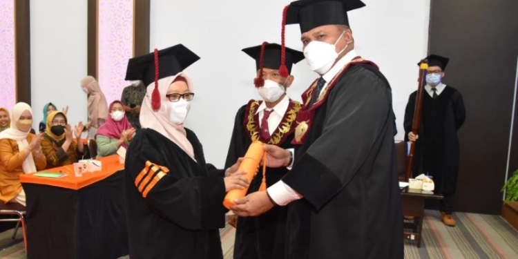 Eduart Wolok mengukuhkan Supartin S.Pd, M.Pd, dengan Gelar Doktor setelah berhasil melewati ujian terbuka disertasi promosi doktor dalam bidang pendidikan IPA, Selasa (8/2/2022), di Aula Pascasarjana UNG. (dok. UNG)