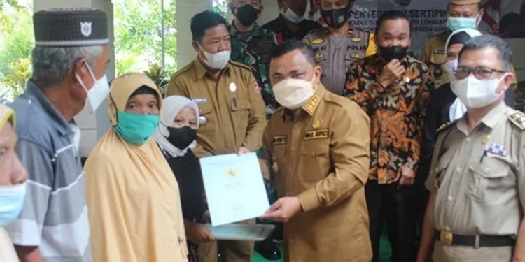 Wakil Bupati Gorontalo, Hendra S. Hemeto, menyerahkan sertifikat tanah kepada seorang penerima manfaat di Desa Molanihu, Kecamatan Bongomeme. (Foto: Istimewa)