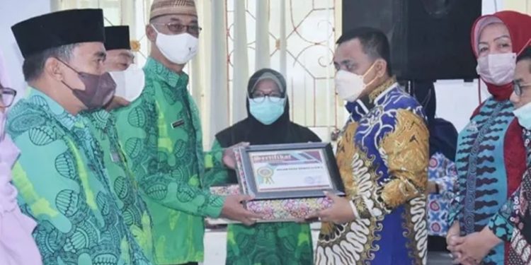 Wakil Bupati Gorontalo, Hendra S. Hemeto, saat menyerahkan penghargaan kepada kader Pembantu Pembina Keluarga Berencana Desa. di Aula Kementerian Agama Kabupaten Gorontalo, Selasa (11/01/2022). (Foto:  Istimewa).