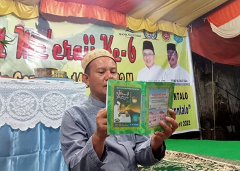 Heriyanto Thalib, sedang memperlihatkan buku dengan naskah Me'eraji yang ditulis dengan huruf arab pegon. Foto : Sari/gopos