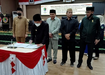 Wali Kota Gorontalo, Marten Taha,  sedang menandatangani berita acara rapat paripurna DPRD kota Gorontalo pembahasan rancangan peraturan daerah (Ranperda) Kota Gorontalo. Rabu (2/3/2022). Foto : Sari/gopos
