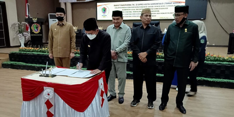 Wali Kota Gorontalo, Marten Taha,  sedang menandatangani berita acara rapat paripurna DPRD kota Gorontalo pembahasan rancangan peraturan daerah (Ranperda) Kota Gorontalo. Rabu (2/3/2022). Foto : Sari/gopos