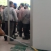 Staf Deprov Gorontalo membersihkan material kaca dari pintu depan yang pecah dalam aksi demonstrasi tentang tambang rakyat di Deprov Gorontalo, Senin (14/3/2022). (muhajir/gopos)