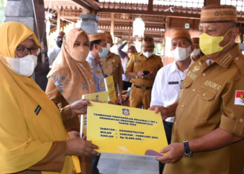 Gubernur Rusli Habibie (kanan), menyerahkan secara simbolis TPP kepada PNS Pemprov Gorontalo di aula Villa Kencana Bolihutuo, Kabupaten Boalemo, Senin (28/3/2022). (Foto: Salman)