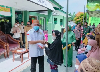 Ketua Dewan Perwakilan Rakyat Daerah (DPRD) Kabupaten Bone Bolango, Halid Tangahu menyalurkan Bantuan Tunai Pedagang Kaki Lima, Warung, dan Nelayan (BT-PKLWN) untuk masyarakat. (Foto: Istimewa)