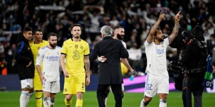 Pemain depan Real Madrid Prancis Karim Benzema (tengah) dan pelatih Real Madrid Italia Carlo Ancelotti berpelukan di akhir pertandingan sepak bola leg kedua perempat final Liga Champions UEFA antara Real Madrid CF dan Chelsea FC di stadion Santiago Bernabeu di Madrid pada 12 April 2022. (Suara.com)