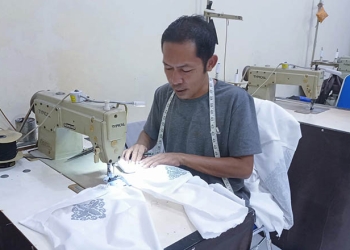 Djonis Bahuwa, salah seorang penjahit pakaian sedang merampungkan orderan pakaian yang diterimanya. (Farun/gopos)