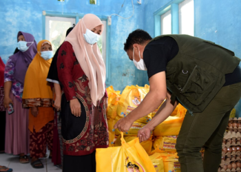 Seorang petugas (kanan) melayani penyaluran BLP3G untuk keluarga penerima manfaat di Kecamatan Bone Pantai, Kabupaten Bone Bolango, Jumat (8/4/2022). (Foto: Haris)