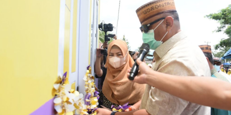 Pengguntingan pita oleh gubernur Rusli Habibie didampingi istri Idah Syahidah saat meresmikan rumah layak huni (Mahyani) bagi korban kebakaran di Desa Bakti, Kecamatan Pulubala, Kabupaten Gorontalo, Jumat (2/15/4/2022). (Foto: Salman)