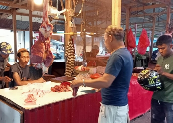 Penjual daging sapi di Pasar Sentral Kota Gorontalo sedang melayani konsumen. Permintaan yang tinggi dan pasokan yang kurang membuat harga daging sapi di Gorontalo masih tinggi H+3 lebaran Idulfitri. (sari/gopos)