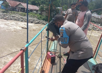 Personel Polsek Suwawa melakukan perbaikan di Jembatan Gantung Tulabolo dengan cara pengelasan. (Foto Istimewa)