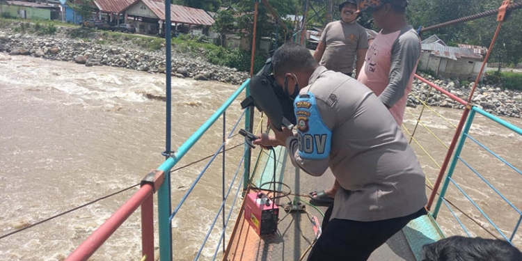 Personel Polsek Suwawa melakukan perbaikan di Jembatan Gantung Tulabolo dengan cara pengelasan. (Foto Istimewa)