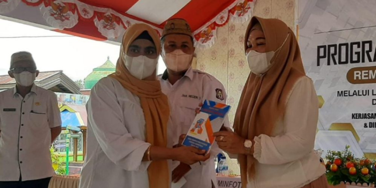 Kabid Pengelolaan Informasi dan Komunikasi Publik Zakiya Baserewan selaku penggagas program Remaja Cakap Digital atau Recak Digital saat meberikan buku panduan cakap digital yang nantinya akan menjadi referensi dalam sosialisasi, pada Kepala Sekolah SMA 1 Kota Gorontalo pada pembukaan kegiatan recak digital, Rabu (11/5/2022). (Foto: Husny Ardy)
