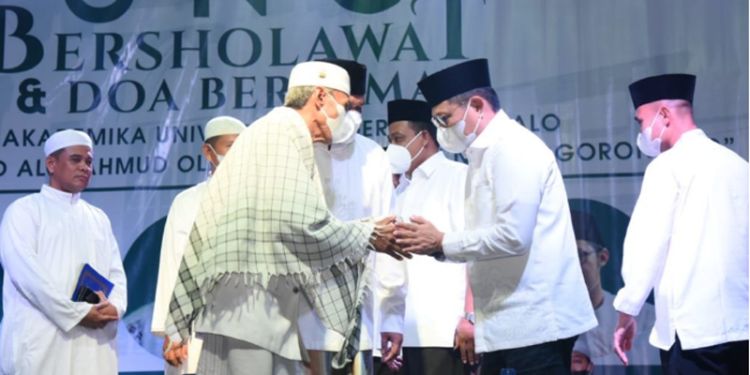 Penjabat Gubernur Gorontalo, Hamka Hendra Noer saat menyapa ustadz KH. Rasyid Kamaru, pada doa bersama untuk Gorontalo dan bersholawat untuk negeri yang dilaksanakan oleh Universitas Negeri Gorontalo (UNG), Selasa malam (24/5/2022). (Foto: Salman)